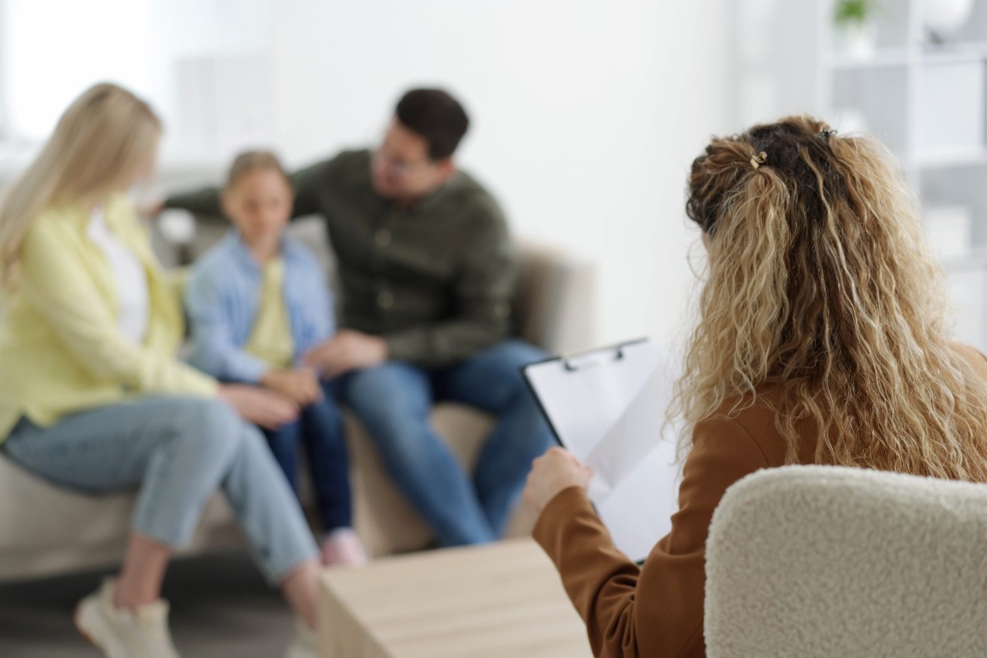 Familia en sesión de terapia con una profesional que toma notas, parte del tratamiento interdisciplinario del ARFID