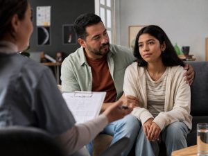 Padre y su hija adolescente en una sesión de terapia familiar con una profesional que toma notas