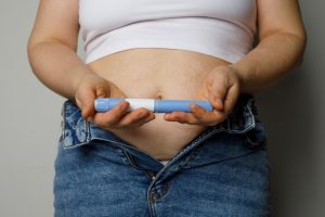 Mujer se aplica una inyección de un medicamento GLP-1 tipo Ozempic en el abdomen